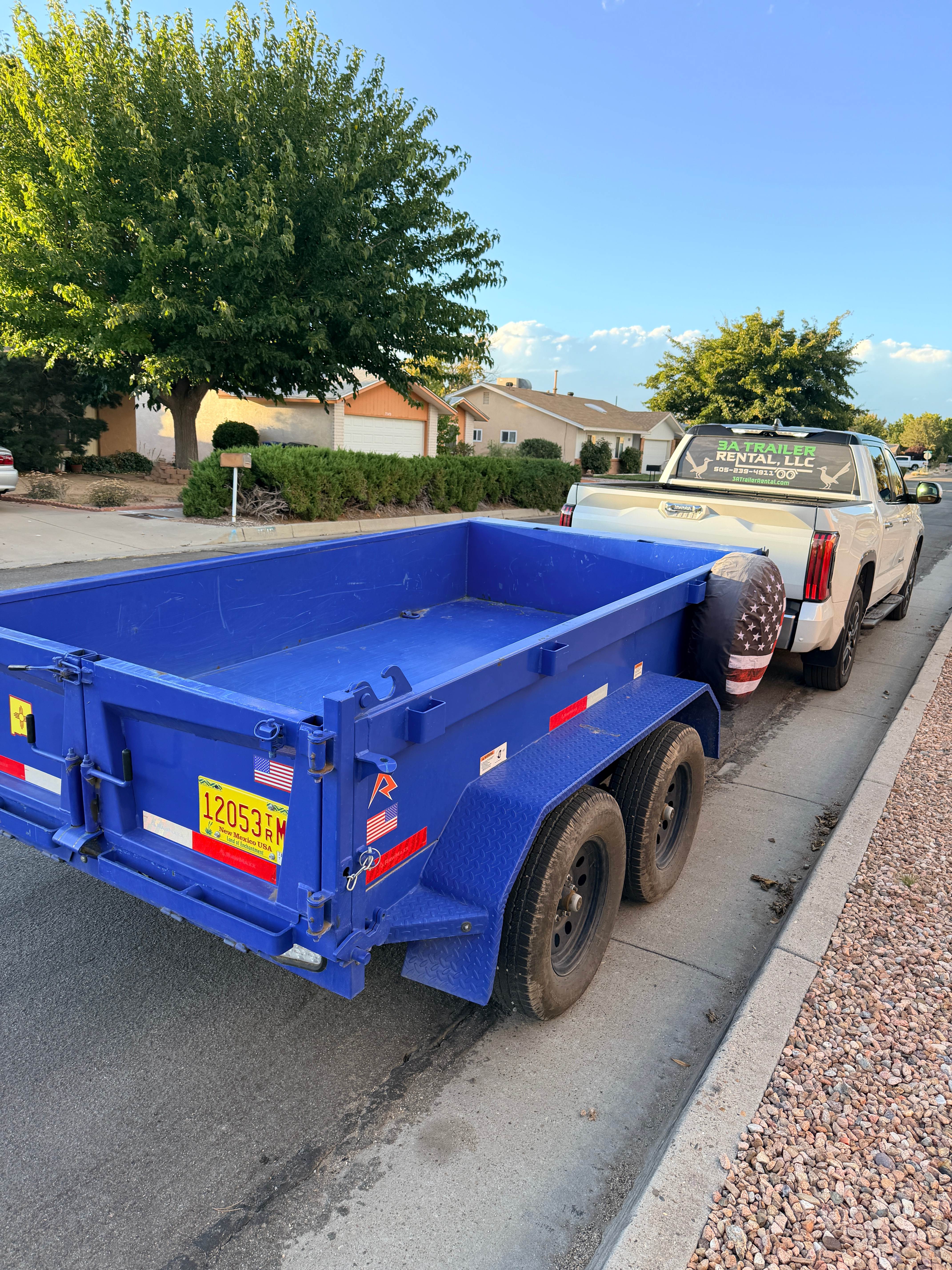 Blue RawMaxx 5x10 hydraulic dump trailer being towed by 3A Trailer Rental truck in Albuquerque