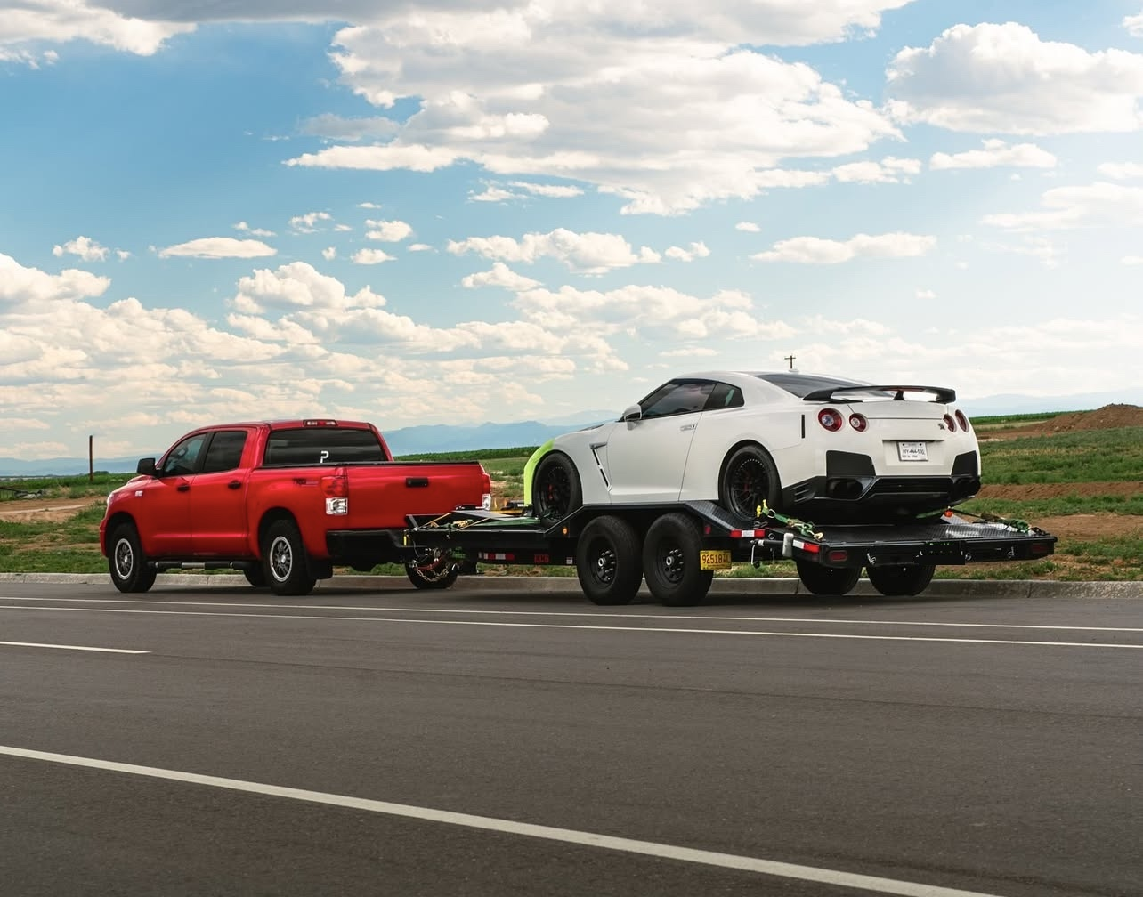 Car hauler trailer transporting a vehicle on a scenic highway